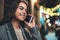 Young smile woman calling mobile phone on background bokeh light in evening street. Girl using smartphone technology. Business