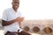 Young smiling African businessman in white shirt and brown pants using phone