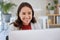 Young smiling asian businesswoman sitting alone in an office and browsing the internet on a computer. Ambitious creative