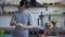 Young smiling Asian man peeling banana standing at countertop in kitchen. Portrait of positive joyful guy having healthy