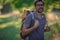 Young smiling backpack man in summer forest nature. Happy handsome male adult student looking at camera walking hiking in forest