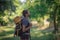 Young smiling backpack man in summer forest nature. Happy handsome male adult student looking at camera walking hiking in forest