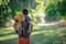Young smiling backpack man in summer forest nature. Happy handsome male adult student looking at camera walking hiking in forest
