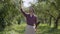 Young smiling bearded caucasian farmer walking through the garden with a spade and pitchfork checking fruit trees