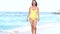 Young smiling beautiful woman in a swimsuit walks along the sea coast. Summer vacation at the sea. Azure waves