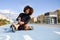 Young smiling black girl sitting on bike line and puts on skates