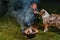 Young smiling blond woman gives biscuits to her tricolor Australian Shepherd dog. In winter, next to the smoking kettle over the