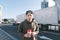 A young smiling boy standing in the street with coffee in his hands. The student stands on the road and truck background. Lifestyl