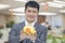 Young smiling businessman holding Chinese piggy bank, portrait