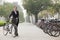 Young smiling businesswoman holding a bicycle on the sidewalk, Beijing