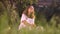 Young smiling caucasian brunette in the park sitting on grass, greaming, thinking