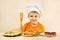 Young smiling chef at the table with ingredients is going to cook hamburger