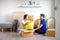 Young smiling couple bonding sitting on floor in new home with boxes on moving day. Happy homeowners or renters just moved into