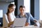 Young Smiling Coworkers Woman and Man Discusing Working Details and Pointing at Laptop Screen in Office