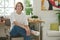 Young smiling craftswoman in stylish casualwear sitting on chair by workplace