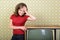 Young smiling ecstatic woman looking at camera in room with vintage wallpaper and retro TV set, retro stylization