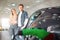 Young smiling family buying first electric car in the showroom. Environmental protection. Modern green vehicle with