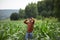 A young smiling farmer stands among a green field of corn