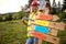 Young smiling female construction worker cheering over wooden table. Construction worker working on wooden house skeleton frame.