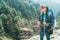 Young smiling female photographer walking Everest Base Camp route at canyon near Suspension Hillary Bridge. Sagarmatha National