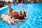 Young smiling fitted girl in bikini, straw hat relax on inflatable swan in swimming pool. Attractive woman in swimwear