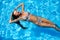 Young smiling fitted woman in bikini relax chilling, swimming on back in clear water in pool. Hot pretty girl in