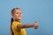 A young smiling girl   givs you an approving gesture against blue background with copy space