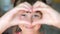Young smiling girl makes heart sign with her hands
