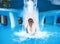 A young smiling girl swimming in the pool with blue clear water. A girl is standing back under a stream of water. Pure