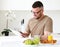 Young smiling handsome man working remotely on tablet in modern kitchen at home