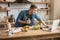 Young smiling man cooking breakfast in the kitchen checking recipe in his laptop , sunday morning