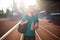 Young smiling man joyfully looking aside with sport bag on shoulder and bottle of water in hand on running track of