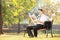 Young smiling man seated on bench reading newspaper in a park