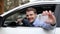 Young smiling man sitting in the car and showing his new driver license