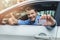 Young smiling man sitting in the car and showing his new driver license with thumb up sign