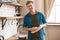 Young smiling man standing in bright well-equipped modern kitchen wiping clean dishes with towel after washing , sunday morning