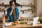 Young smiling man talking on the phone while cooking breakfast in the kitchen checking recipe in his laptop , sunday morning