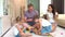 Young smiling parents and two little children playing board game at home