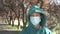 Young smiling patient in a protective medical mask and a hood against the background of the road and trees.