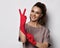 Young smiling pretty brunette woman doctor gynecologist in red latex gloves standing showing peace good sign with