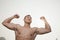 Young, smiling, shirtless young man flexing his muscles with arms raised outdoors in Beijing, China