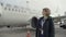 Young smiling stewardess stands on the background of airplane