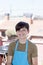 Young smiling teenager standing at terrace wearing a gardener apron