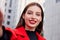 Young, smiling and unsurpassed girl with large round earrings takes a selfie against a gray building