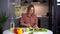 Young smiling vegetarian woman preparing healthy vegan food alone at home.