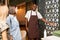 Young smiling waiter in workwear inviting two girls to one of luxurious halls