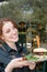 A young smiling waitress with freckles is holding a burger with meat. Service in the restaurant concept