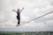 Young smiling woman balancing with arms raised on the slackline rope