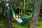 Young smiling woman in dark sunglasses lies in hammock