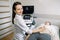 Young smiling woman doctor sonographer using ultrasound machine while conducting ultrasound test of female patient